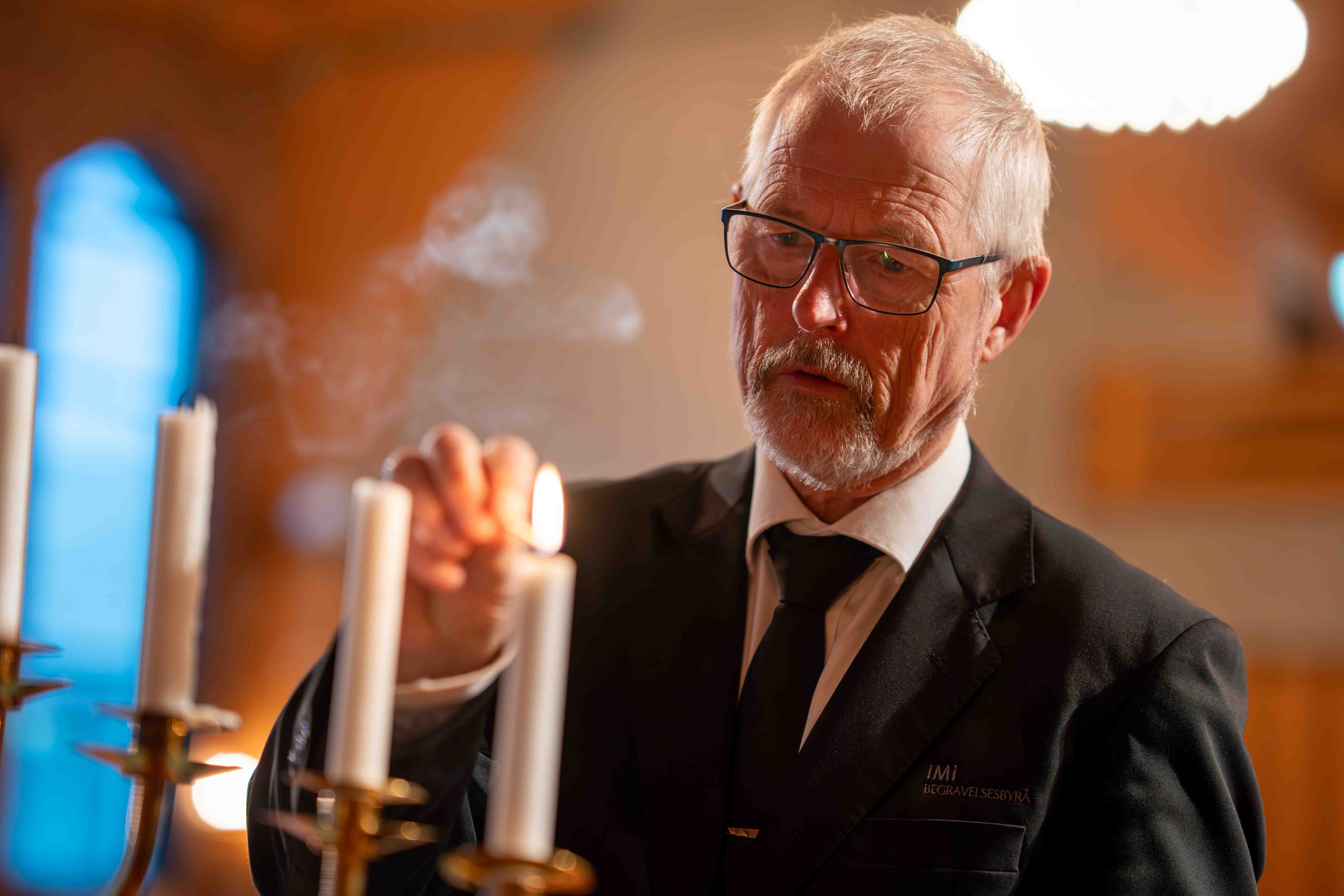 Medarbeider hos iMi tenner lys i kirkerom